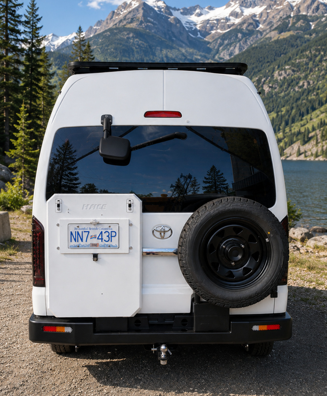 Toyota HiAce H200 2004–2018 heavy-duty steel rear bumper with spare tire carrier, storage box mount, integrated reflectors and tow hitch, shown installed on a white HiAce van.