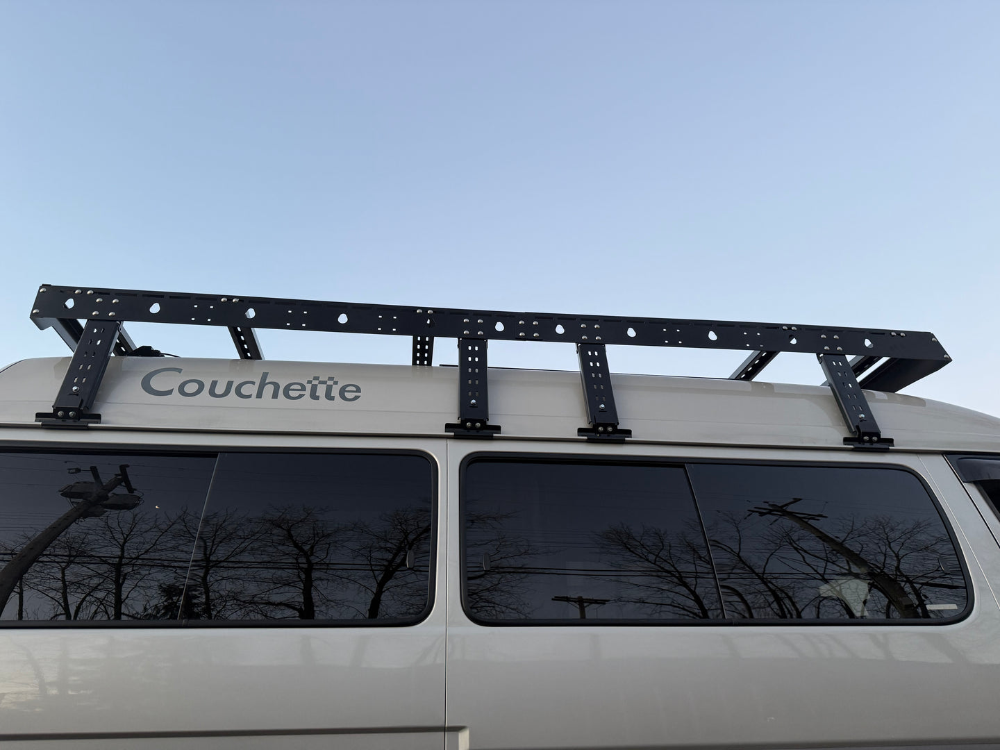 Roof rack on a van with 'Couchette' branding against a clear sky.