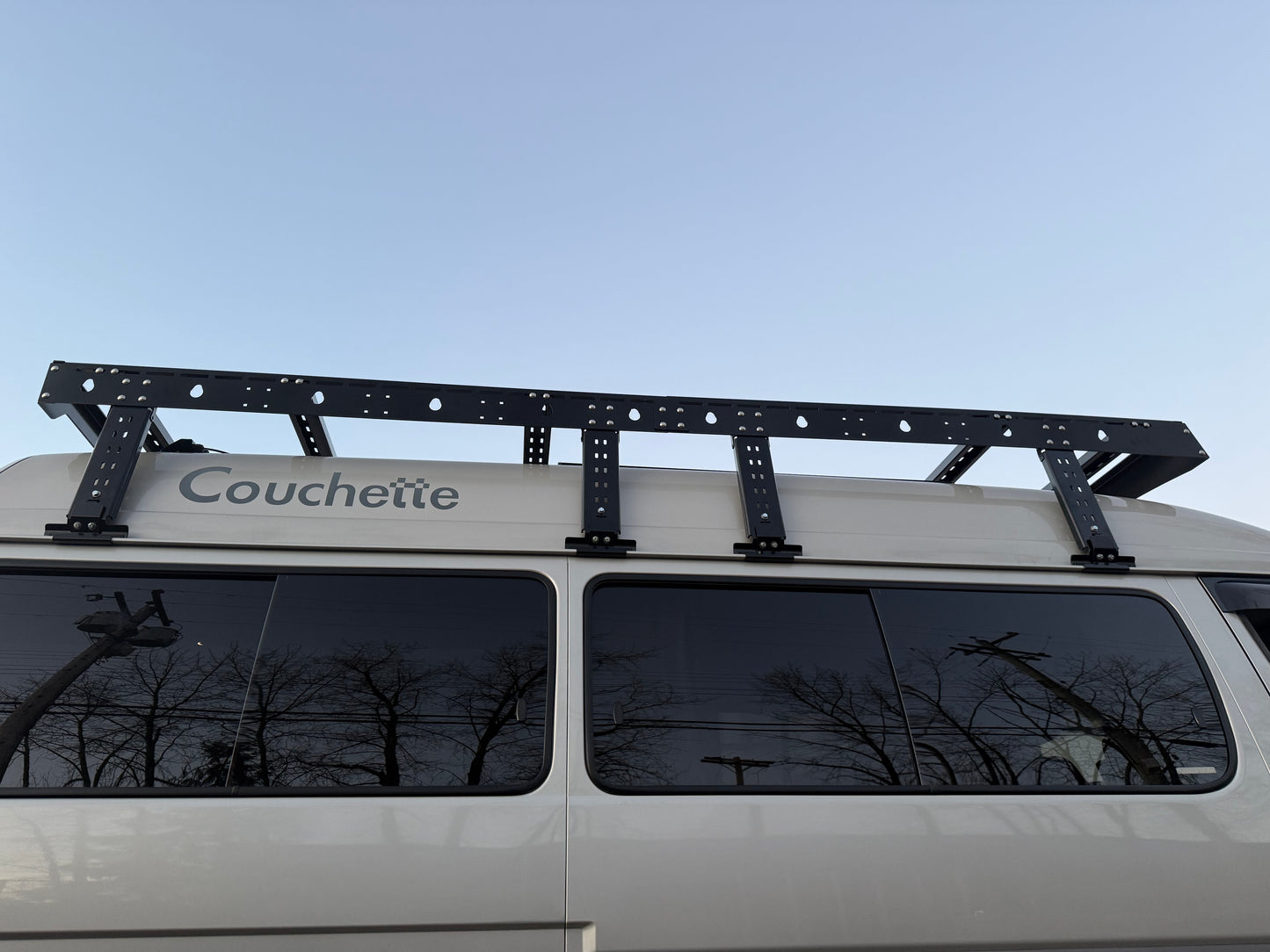 Roof rack on a van with 'Couchette' branding against a clear sky.